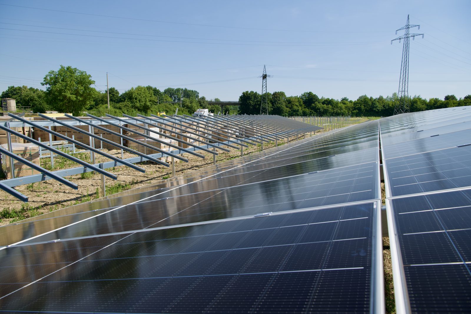 PV-Park Oberstimm im Bau: fertig belegte Modulreihen neben Unterkonstruktion mit bereitgestellten Modulpaletten